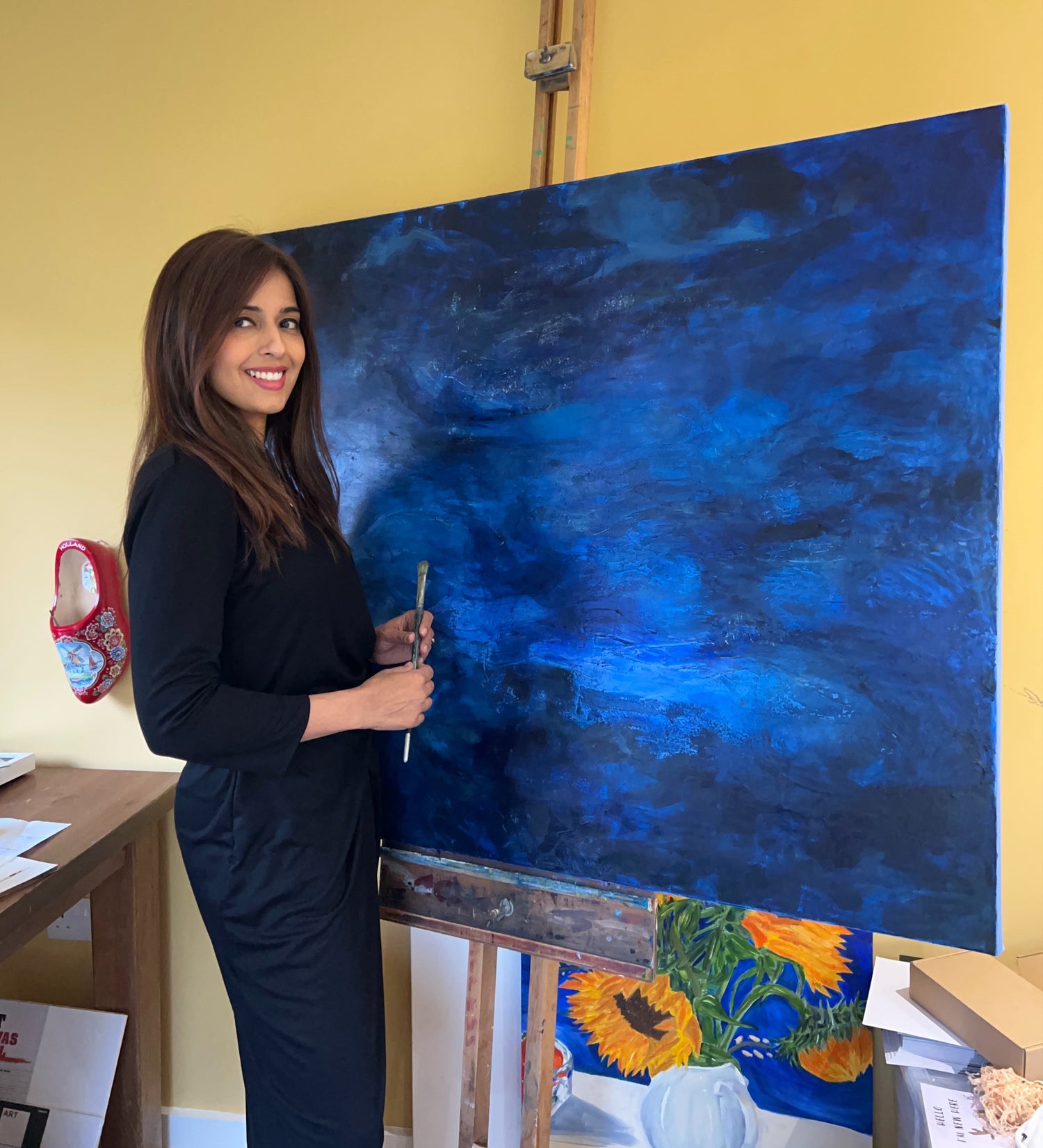 Mishi next to a celestial Galaxy painting in her studio